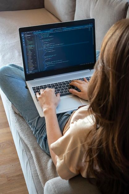 Premium Photo | A woman working on a laptop while sitting on the sofa A young girl programmer is coding